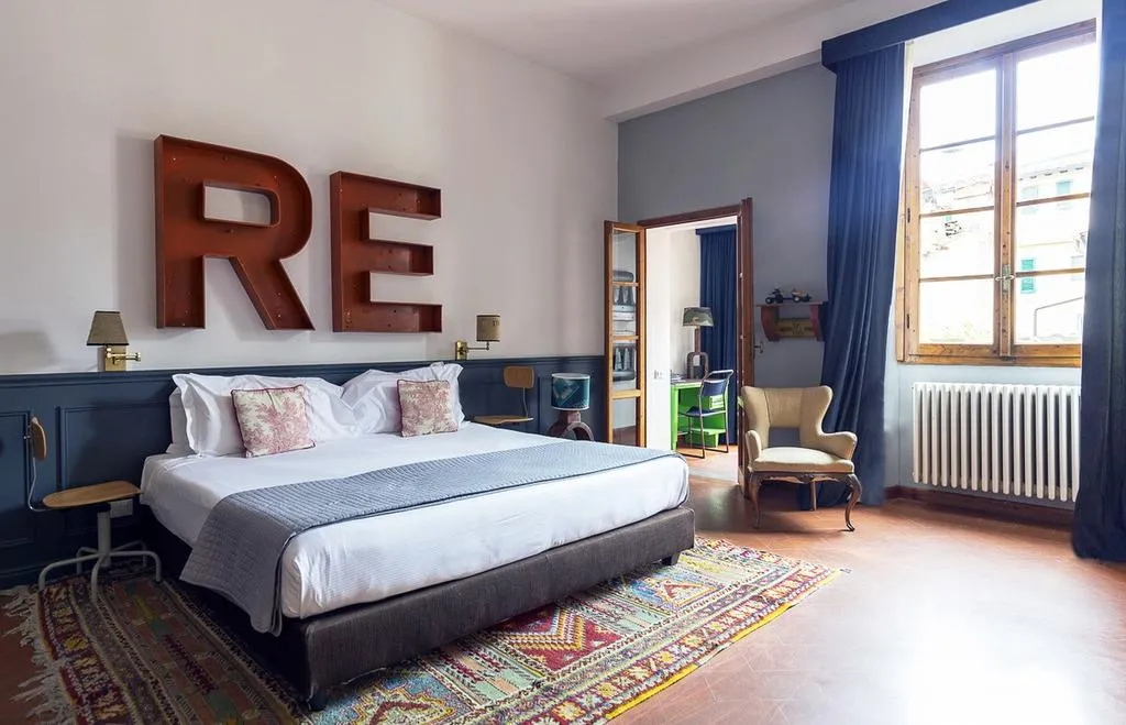 Camera da letto SoprArno Suite con libreria in ferro sovrastante il letto a forma di R.E.